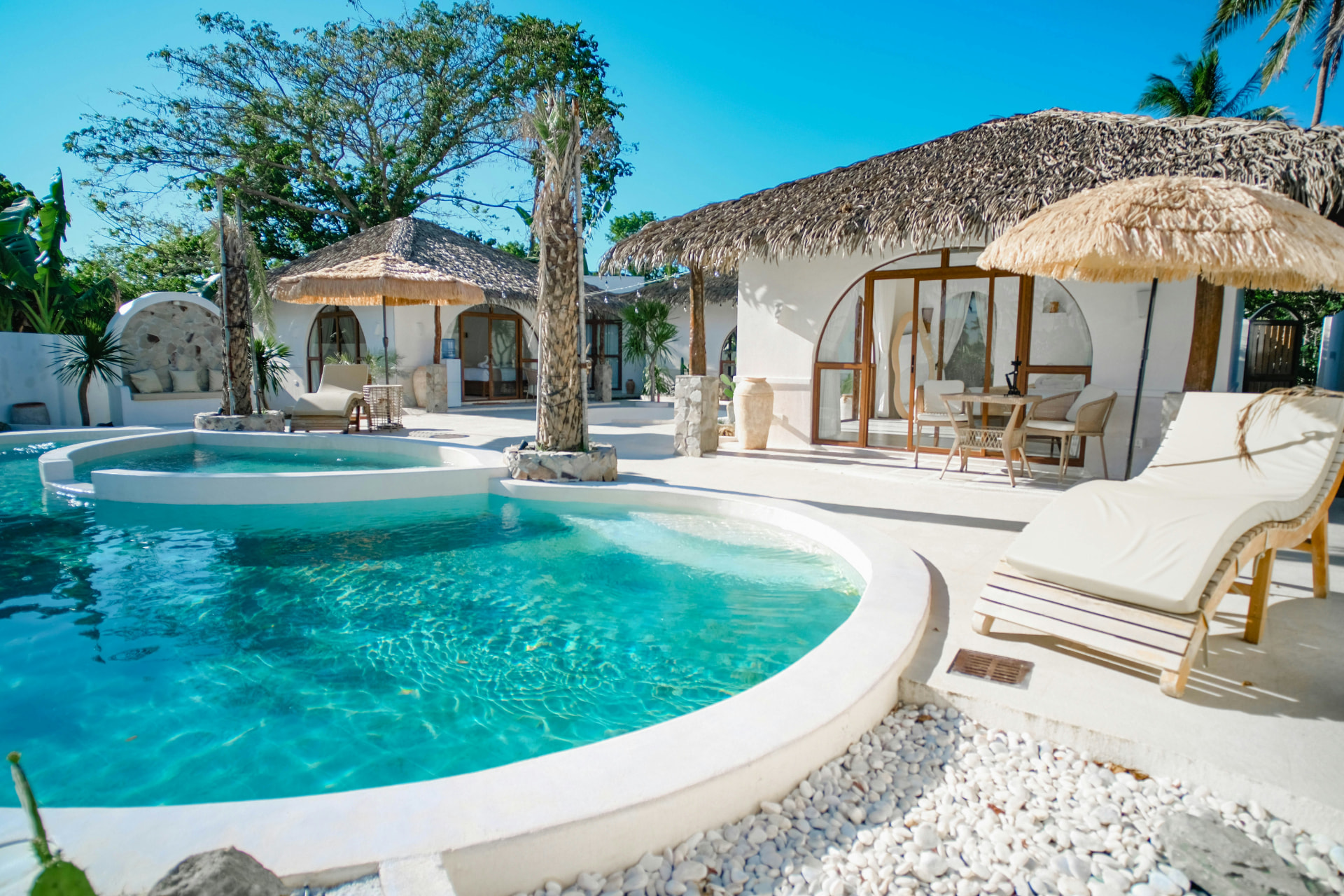 A private villa pool with turquoise water and thatched umbrellas