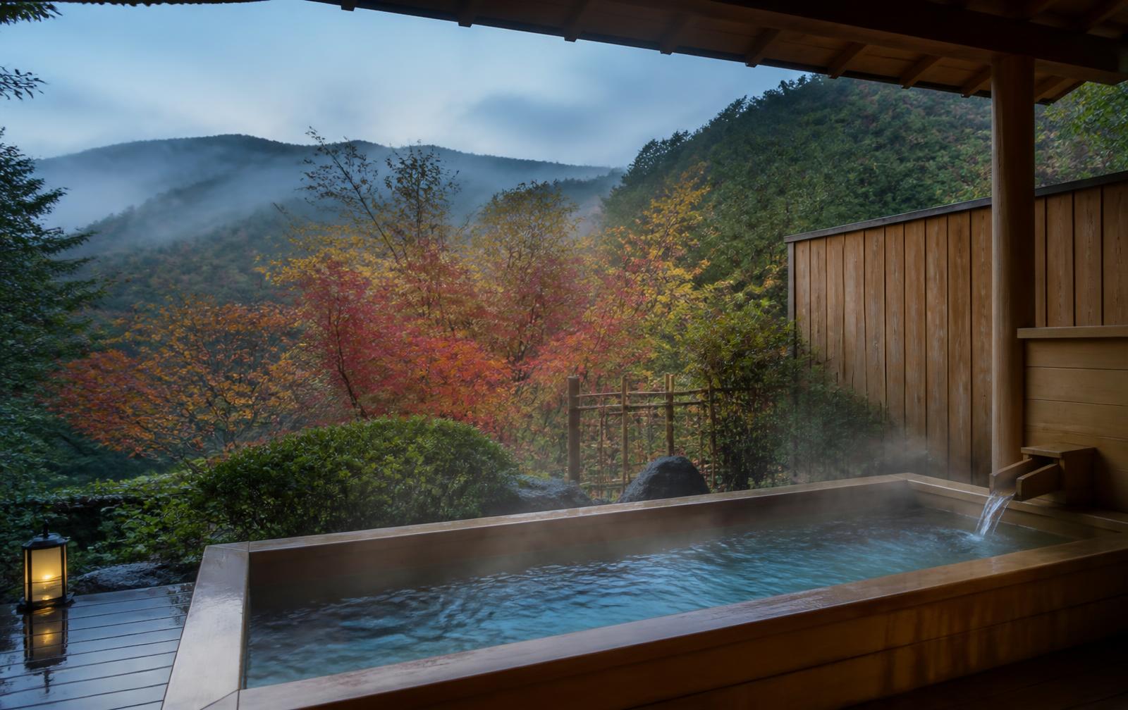 A steaming private open air onsen bath overlooking misty mountains in Hakone