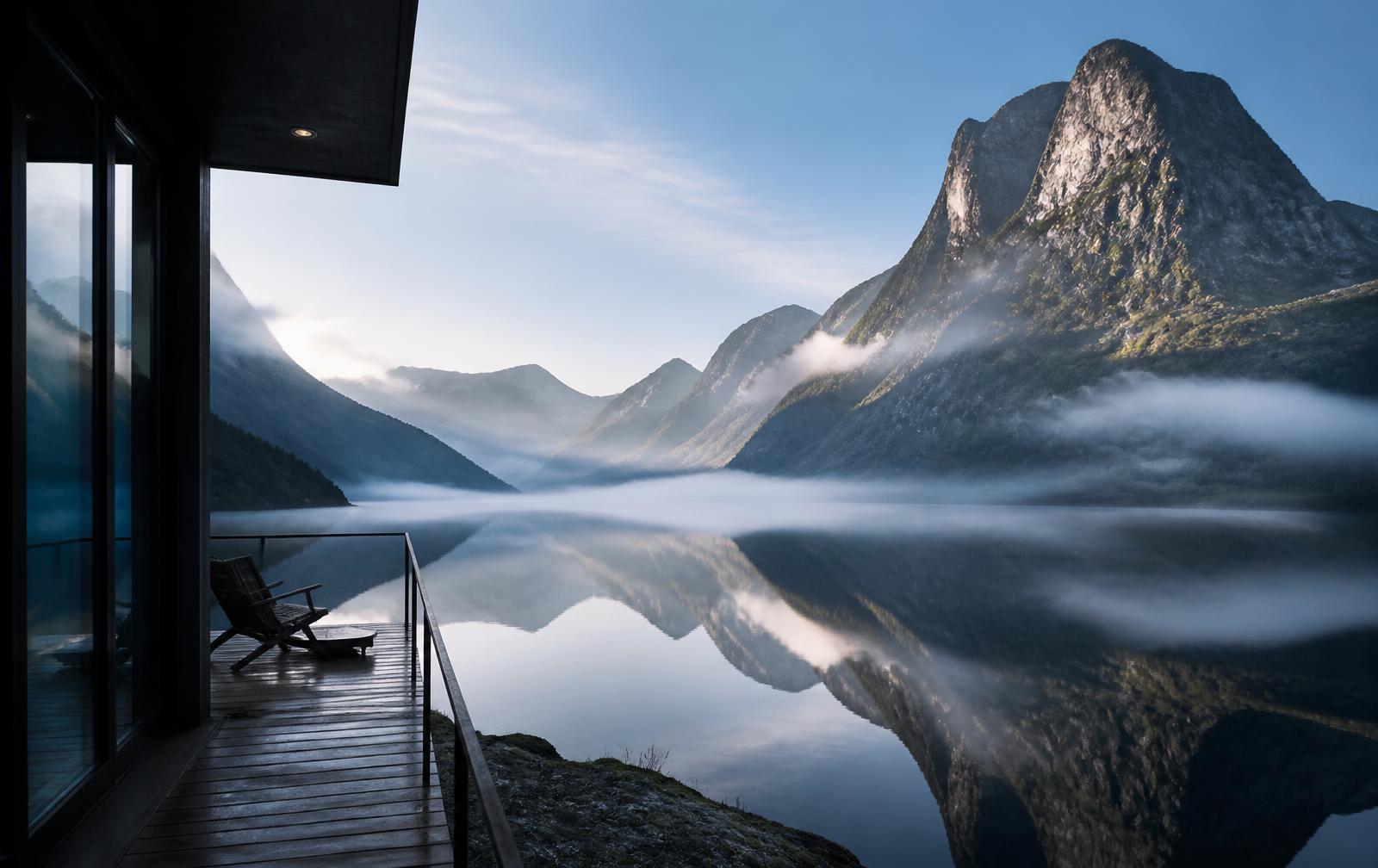 Still water and vast granite mountains in a Norwegian fjord at dawn